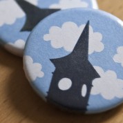 Close-up of the badge designed for Clevedon Pride. The Clock Tower's silhouette against a blue sky and fluffy clouds.